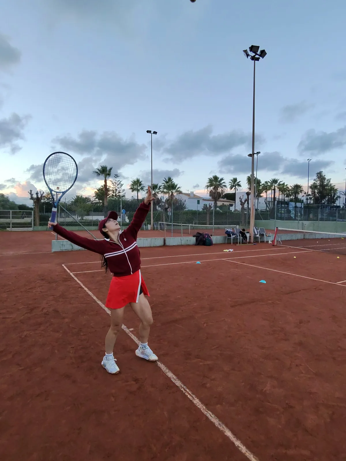 Tennis player serving at dusk on a Mallorca clay court
